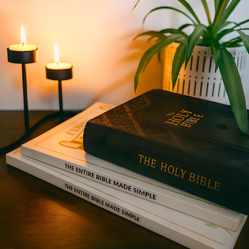 May include: A stack of books with the text "THE ENTIRE BIBLE MADE SIMPLE" and "THE HOLY BIBLE" in gold lettering. A black leather-bound Bible rests on top. Two lit candles in black metal holders are in the background.