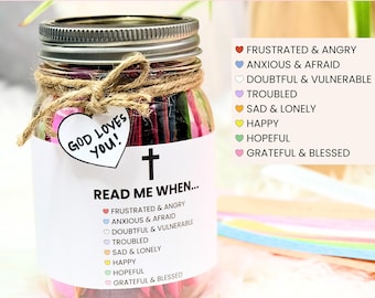 May include: A printable DIY Bible verse jar with a white label that says "Read Me When..." and lists different emotions with corresponding Bible verses. The jar is filled with colorful paper strips. The label also includes a heart with a cross and the text "God Loves You!"