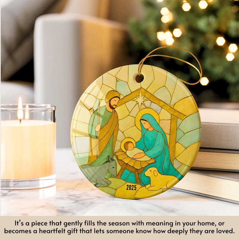 May include: A round Christmas ornament featuring a Nativity scene with Mary, Joseph, and baby Jesus. The ornament has a gold string for hanging and the year 2025 is printed on the bottom. The artwork is in shades of green, blue, and yellow.