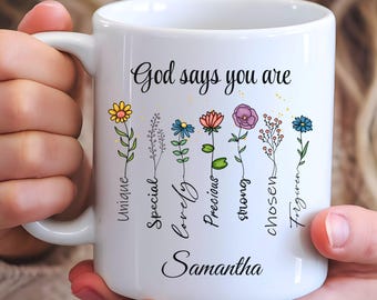 May include: White ceramic mug with a floral design and the text "God says you are" with words "unique, special, lovely, precious, strong, chosen, forgiven" written vertically next to each flower. The name "Samantha" is written at the bottom of the mug.