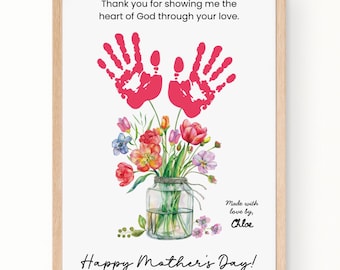 May include: A framed print with a light wood frame. The print features two red handprints above a watercolor bouquet in a glass jar. Text includes "Thank you for showing me the heart of God through your love" and "Happy Mother's Day!"