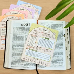 Puede incluir: Una Biblia abierta con el libro de Jueces, acompa&ntilde;ada de coloridas tarjetas de estudio con nombres de libros b&iacute;blicos como Jerem&iacute;as y Proverbios. Las tarjetas proporcionan res&uacute;menes e informaci&oacute;n clave.