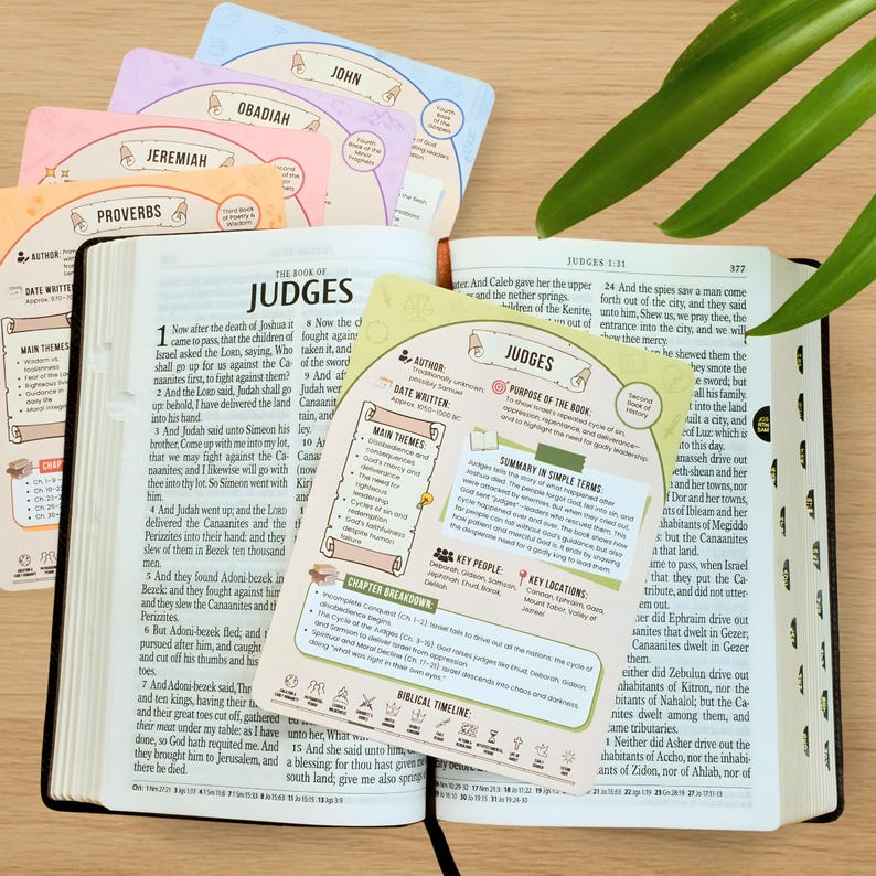 Puede incluir: Una Biblia abierta con el libro de Jueces, acompa&ntilde;ada de coloridas tarjetas de estudio con nombres de libros b&iacute;blicos como Jerem&iacute;as y Proverbios. Las tarjetas proporcionan res&uacute;menes e informaci&oacute;n clave.
