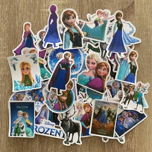 Könnte beinhalten: Eine Sammlung von Frozen-Stickern mit verschiedenen Charakteren aus dem Film, darunter Elsa, Anna, Olaf und Kristoff. Die Sticker sind bunt und zeigen verschiedene Posen und Gesichtsausdrücke. Einige Sticker haben Text, darunter "Frozen" und "Frozen II".