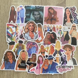 Può includere: Una collezione di adesivi colorati con immagini di una pop star, tra cui un primo piano del suo viso, una foto a figura intera e un'illustrazione in stile cartone animato. Gli adesivi includono anche testo come "Britney", "It's Britney, Bitch!" e "Never Forget".