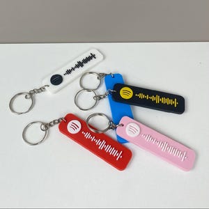 Peut inclure: Plusieurs porte-clés Spotify de couleurs variées : blanc, rouge, bleu, noir et rose. Chaque porte-clés présente un code Spotify unique et un anneau argenté. Les porte-clés sont rectangulaires et faits d'un matériau lisse.