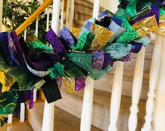 May include: A Mardi Gras garland made of fabric scraps in green, purple, and gold. The garland is decorated with glitter and sequins.