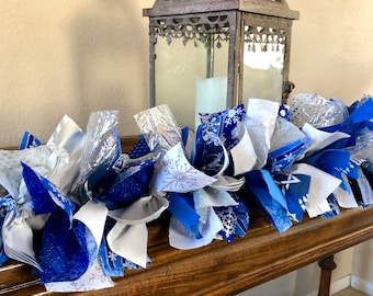 May include: A blue and white fabric garland with snowflake patterns. The garland is made of various fabrics, including blue, white, and silver. It is perfect for decorating for the winter holidays.