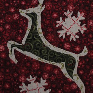 Può includere: Un tessuto natalizio festivo con una renna che salta e fiocchi di neve. La renna è bianca con un interno a motivi verdi e oro, su uno sfondo rosso con motivi a stella. I fiocchi di neve hanno la scritta "Christmas".