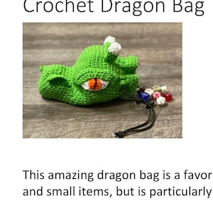 Puede incluir: Bolsa de drag&oacute;n de ganchillo verde con un cuerno blanco y un ojo naranja. La bolsa est&aacute; abierta y tiene cordones de ajuste negros. Hay dados dentro de la bolsa.