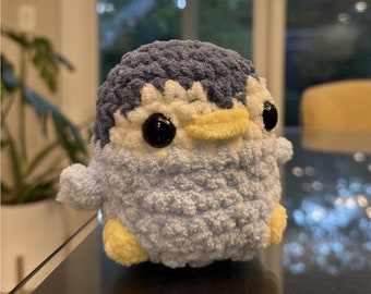 May include: A small blue and yellow crocheted penguin plush toy with black eyes.