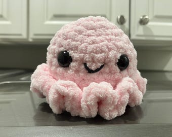 May include: A pink crocheted octopus plush toy with black eyes and a smiling mouth.