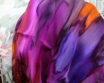 Puede incluir: Una bufanda de seda con un diseño abstracto vibrante en tonos de morado, rosa, naranja y negro.