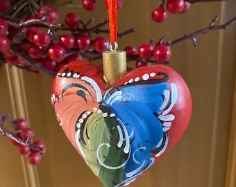 May include: A red heart-shaped ornament with a gold top and a painted design of swirling blue, green, and white lines.