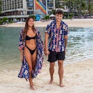 Puede incluir: Un kimono de playa azul marino con un vibrante estampado geométrico y floral en rosa, blanco y naranja, combinado con una camisa azul marino de manga corta a juego, con cuello y un estampado intrincado y multicolor similar.
