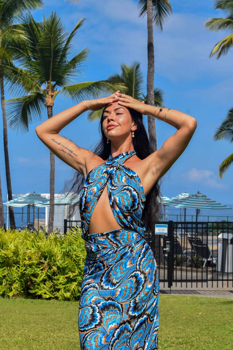 May include: A blue and black patterned halter dress with a matching skirt. The dress has a keyhole cutout and is worn outdoors with palm trees in the background.