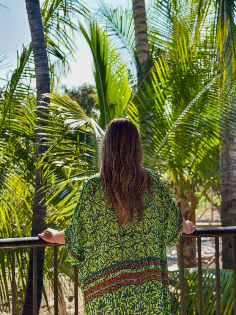 May include: A loose-fitting kimono-style garment featuring a vibrant lime green base with a dark green and red floral and paisley pattern. The fabric displays a wide horizontal border at the hem with intricate red and dark green decorative motifs.