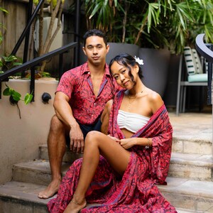 May include: A red and black leaf-patterned short-sleeve button-down shirt and a matching long, open-front robe with blue trim. The robe is worn over a white strapless tube top. The garments feature a consistent botanical print throughout.