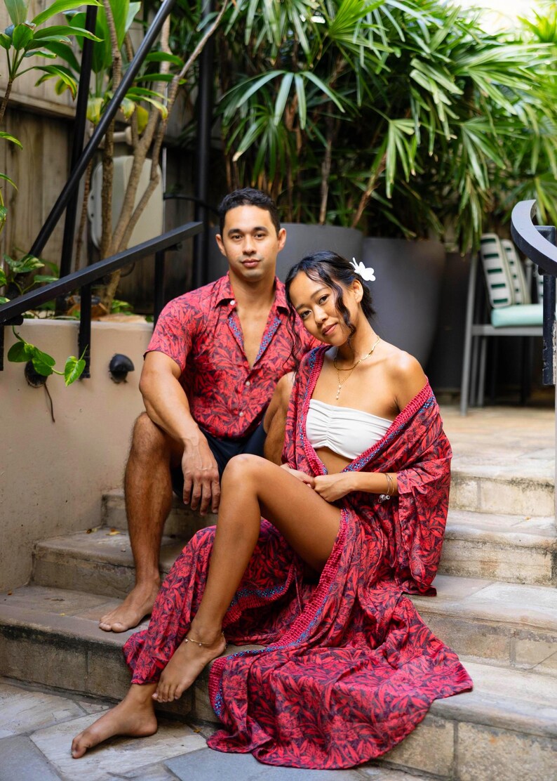 May include: A red and black leaf-patterned short-sleeve button-down shirt and a matching long, open-front robe with blue trim. The robe is worn over a white strapless tube top. The garments feature a consistent botanical print throughout.