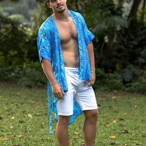 May include: A bright blue open-front kimono featuring a detailed paisley and floral pattern in shades of cyan and navy, paired with crisp white tailored shorts that reach above the knee, creating a coordinated ensemble for warm weather.