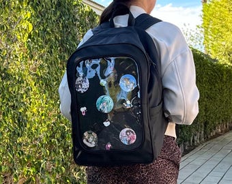 May include: Black backpack with a clear plastic panel on the back. The panel has several colorful round stickers with anime characters on them.