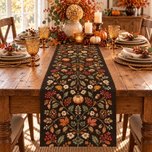 May include: A dark brown table runner featuring a symmetrical botanical print of orange pumpkins, red berries, pinecones, acorns, and autumn leaves in shades of green, gold, and rust, centered on a wooden dining table with place settings.