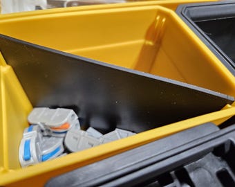 May include: A yellow plastic storage container with a black divider. The container is filled with small gray plastic parts.