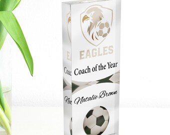 Può includere: Un premio di calcio rettangolare trasparente con la scritta "EAGLES Coach of the Year" e una grafica di pallone da calcio. Il premio include anche il nome "Natalie Brown". Il premio è alto circa 15 cm.