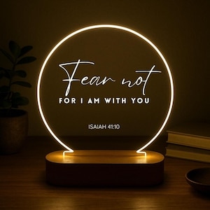 May include: A decorative LED lamp with a circular light design. The lamp features the text "Fear not, for I am with you" and "Isaiah 41:10". The base is a rectangular shape with a wooden finish.