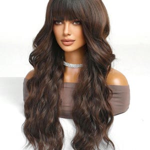 A woman with long, wavy brown hair wearing a brown top and a necklace.