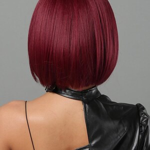 the back view of a person with short, dark red hair. The person is wearing a black leather jacket.