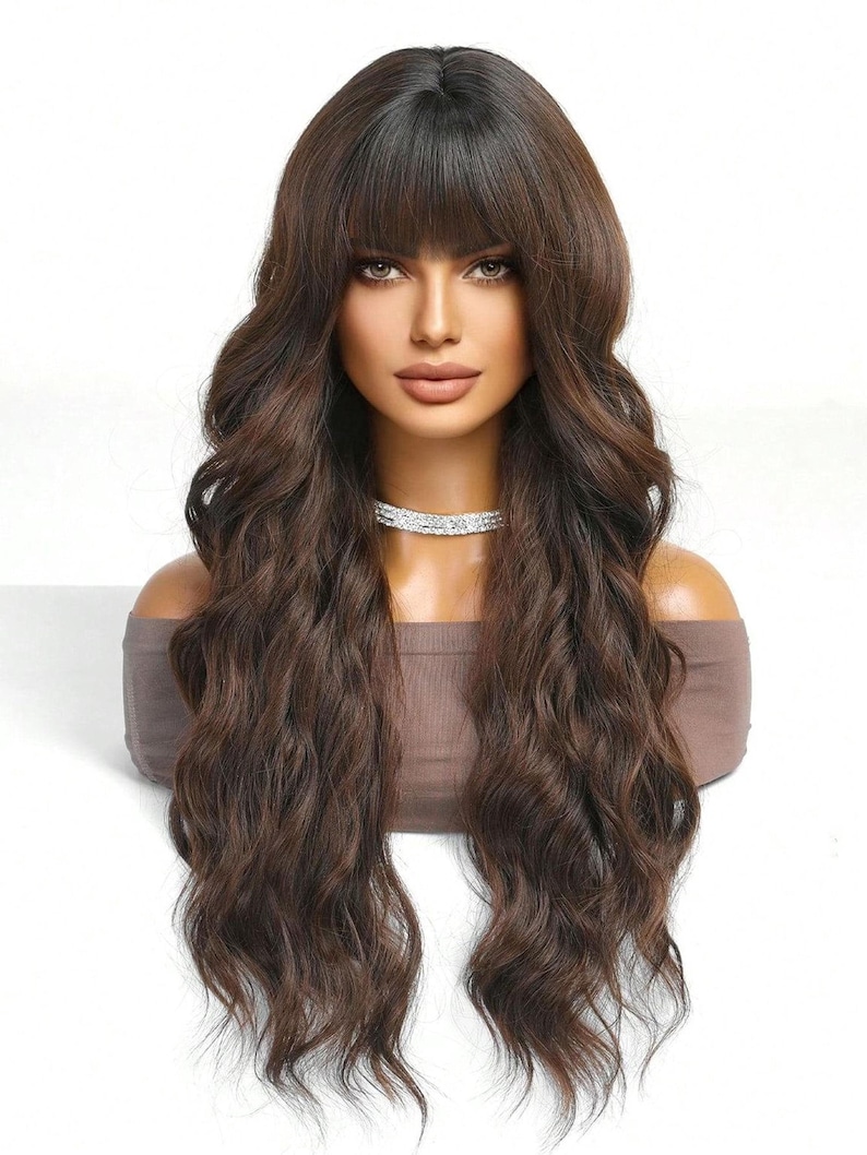 A woman with long, wavy brown hair and bangs is shown in a close-up portrait against a white background.