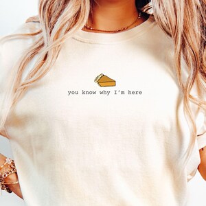 May include: A white t-shirt with a small pie graphic and the text "you know why I'm here".