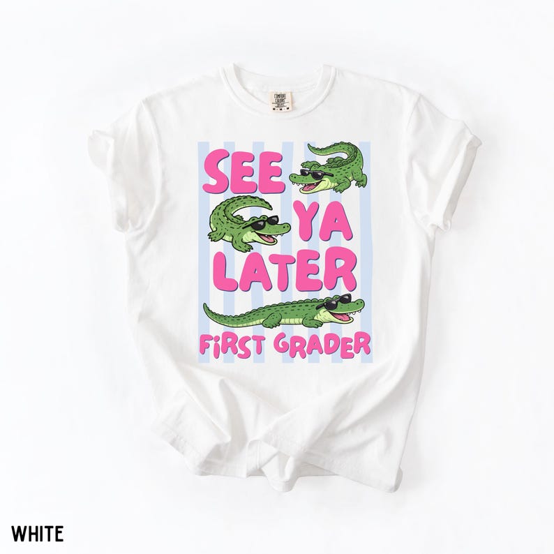K&ouml;nnte beinhalten: Ein wei&szlig;es T-Shirt mit einem Grafikdruck von drei gr&uuml;nen Alligatoren, die eine schwarze Sonnenbrille tragen. Der Text "SEE YA LATER FIRST GRADER" steht in rosa Buchstaben vor einem Hintergrund aus hellblauen vertikalen Streifen.