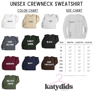 Puede incluir: Una tabla de colores y tallas para una sudadera unisex de cuello redondo. La imagen muestra once opciones de color, incluyendo blanco, arena, ceniza, gris oscuro, verde bosque, negro, granate, marino, chocolate oscuro y verde militar, con tabla en pulgadas.