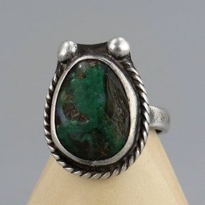 May include: A silver ring featuring a green and brown stone set within a rope-like design.