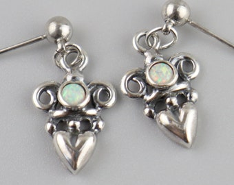 May include: A pair of silver earrings with a heart-shaped design and a small white opal stone in the center of each earring.