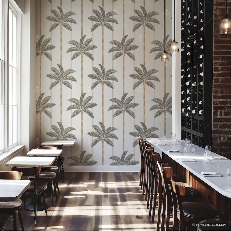 Pu&ograve; includere: Un interno di sala da pranzo con una parete bianca con un motivo ripetitivo di palme. La stanza ha un lungo tavolo di legno con sgabelli da bar e un bancone in marmo bianco. Il tavolo &egrave; apparecchiato con bicchieri e piatti.