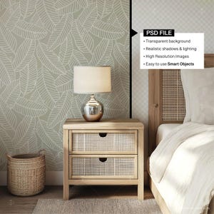 May include: A wooden nightstand with two drawers and a woven rattan front. A silver lamp with a white lampshade sits on top of the nightstand. A woven basket sits on the floor next to the nightstand. The nightstand is in front of a wall with a white leaf pattern.