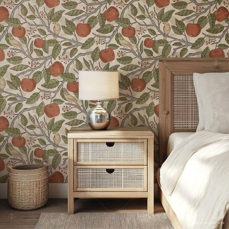 May include: A bedroom with a patterned wallpaper featuring branches, leaves, birds, and apples. A wooden nightstand with two drawers sits next to a bed with a white duvet and a woven headboard. A lamp with a white shade sits on the nightstand.
