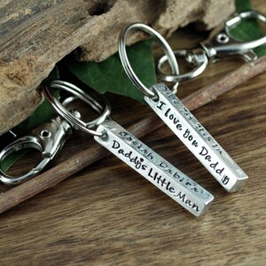 May include: Two silver keychains with engraved bars. One bar reads "I love you Daddy" and the other reads "Daddy's Little Man".