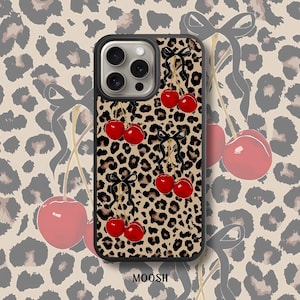 May include: A black phone case with a leopard print design and red cherries. The case has a cutout for the camera lens and a raised lip around the edges to protect the screen.