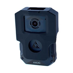 May include: A black body-worn camera with a lens and the word "AXON" printed on the front. The camera has a triangular logo and a textured grip. The device is designed for law enforcement and security applications.