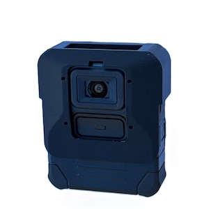 May include: A navy blue body camera with a rectangular shape. The camera has a lens and a rectangular compartment. The device is designed with a rugged exterior and is likely used for recording.