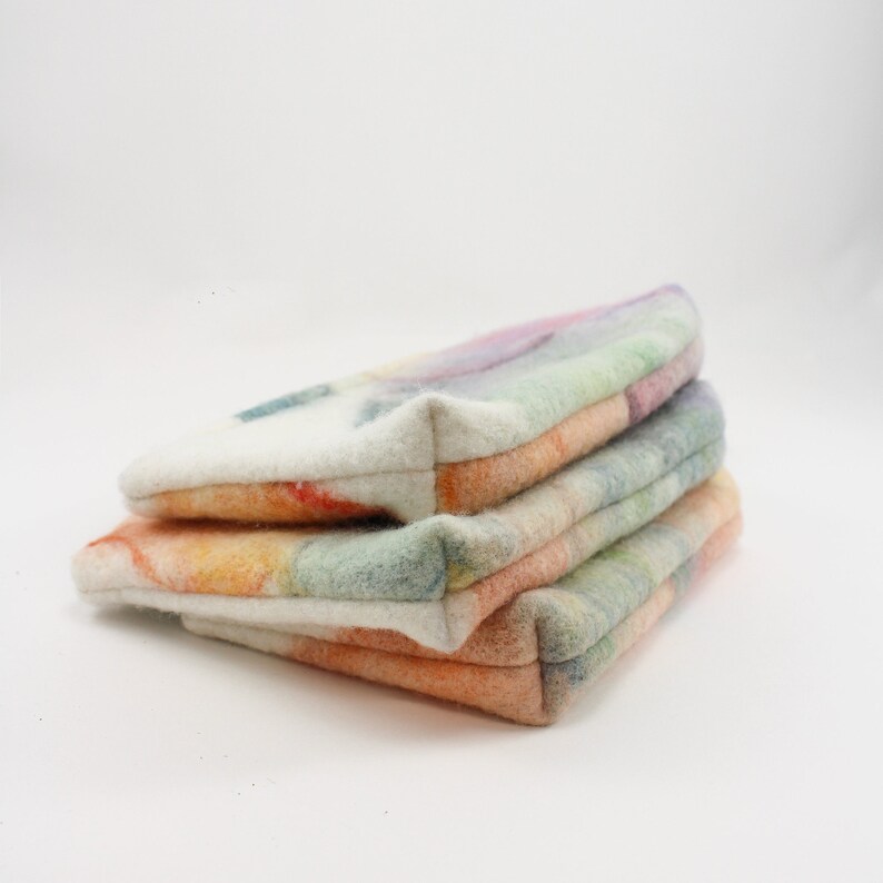 May include: Three colorful felted fabric pouches stacked on top of each other. The pouches are made of a soft, textured fabric and have a variety of colors, including white, orange, yellow, green, and purple.