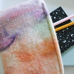 May include: A fuzzy, rainbow-colored zippered pouch with a black and white notebook with stars and moons inside.