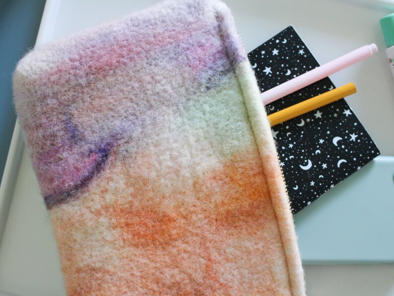 May include: A fuzzy, rainbow-colored zippered pouch with a black and white notebook with stars and moons inside.