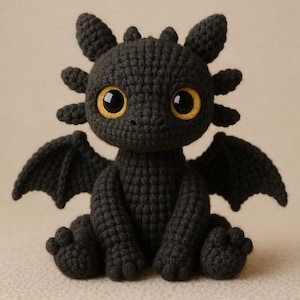 May include: A handmade black crochet dragon with large yellow eyes, small wings, and pointed ears. The dragon is sitting, with its legs and wings spread out. The crochet stitches are visible, giving the dragon a textured appearance.