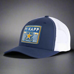 May include: Navy blue and white trucker hat with a patch featuring the text "PI KAPP" and a gold star. The hat has a curved brim and a mesh back for breathability.