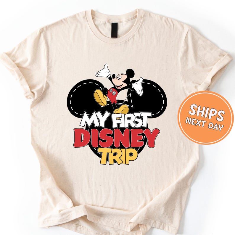 A white t-shirt with a graphic design featuring Mickey Mouse and the text "My first Disney trip" printed on it.